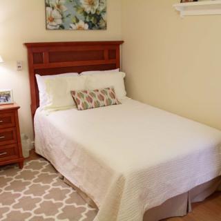 A cozy bedroom with a neatly made bed, wooden nightstand, and decorative painting.