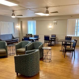 A cozy lounge area with various chairs, tables, and large windows.