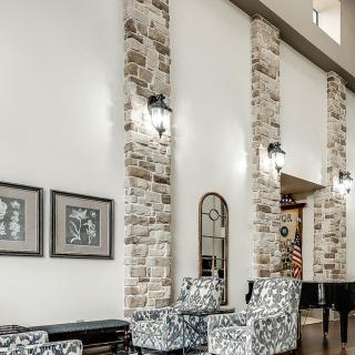 A modern living room featuring stone wall accents, high ceilings, and contemporary furniture.