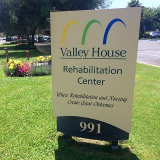 Sign for the Valley House Rehabilitation Center located outdoors with landscaping.