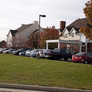 A view of a parking lot filled with cars in front of a residential or commercial building.