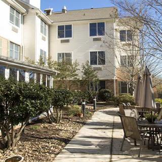 A sunny day in the courtyard of a residential building with outdoor seating and a paved pathway.