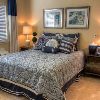 A cozy bedroom with a neatly made bed, decorative pillows, and ambient lighting.