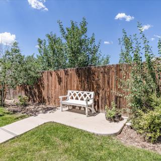 A serene garden space featuring a white bench surrounded by greenery and a wooden fence.