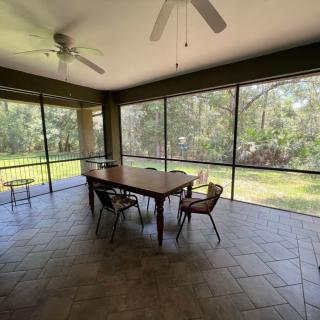 A screened patio with a central table and chairs, overlooking a lush outdoor area.