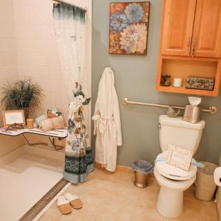 A cozy bathroom featuring a shower, toilet, and artfully decorated with plants and wall art.