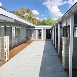 A modern courtyard with air conditioning units and a paved walkway under a clear blue sky.