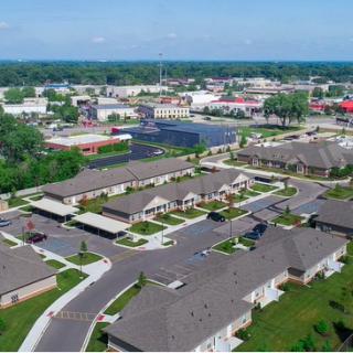 Aerial view of a suburban residential area with houses, streets, and surrounding greenery.