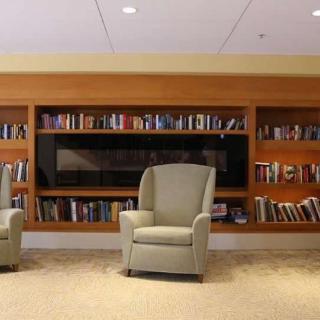 A cozy library reading area with comfortable chairs and a full bookshelf.