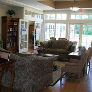 A cozy living room with sofas, bookshelves, and large windows letting in natural light.