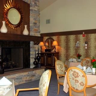 A cozy dining room with a fireplace, elegantly set tables, and decorative elements.