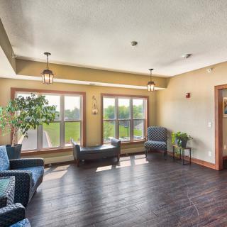 A cozy living room with large windows, comfortable seating, and wooden flooring.