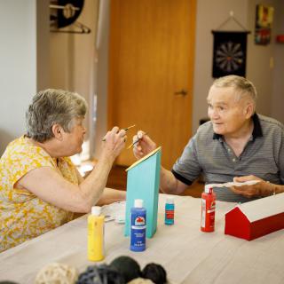 An elderly couple engaged in a fun painting activity together.