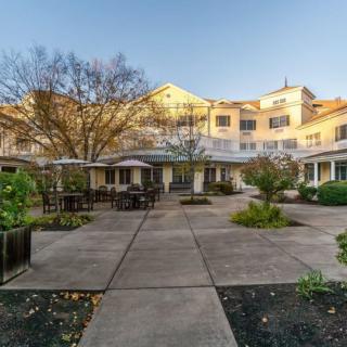 A residential building with a courtyard featuring patio furniture and surrounding trees.