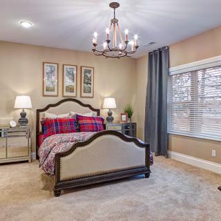 A cozy, well-decorated bedroom featuring a stylish chandelier and elegant furniture.