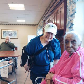 A caregiver shares a warm moment with an elderly woman in a senior living facility.