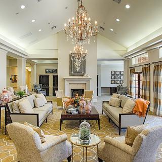A luxurious living room featuring a grand chandelier, comfortable seating area, and an elegant fireplace.