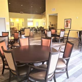 A spacious dining area with multiple tables and chairs, featuring a warm color palette.