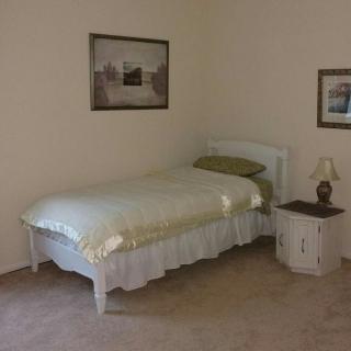 A simple bedroom with a single bed and nightstand.