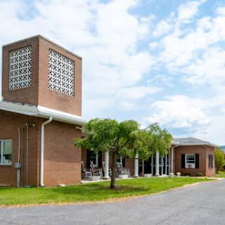 A modern brick building surrounded by greenery under a partly cloudy sky.