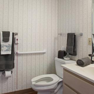 A compact bathroom with a toilet, sink, and neatly arranged towels against a paneled wall.