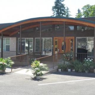 A modern building with large glass windows and a landscaped entrance.