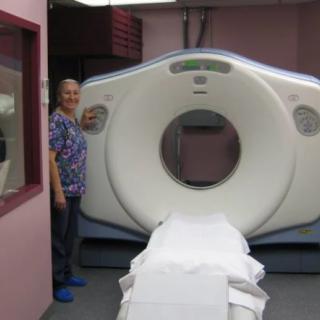 A healthcare professional standing next to a CT scanner in a medical facility.