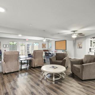 A spacious living room featuring comfortable armchairs, a round coffee table, and modern wood flooring.