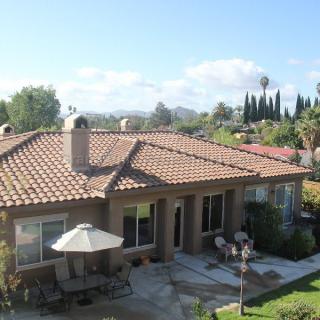 A sunny backyard view of a house with a patio and garden.