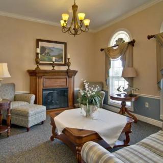 A cozy living room featuring traditional decor with a fireplace, chandelier, and comfortable seating.