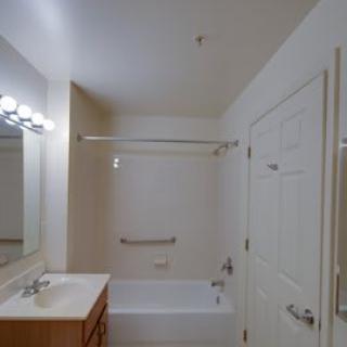 A clean and simple bathroom featuring a bathtub, sink with a mirror, and modern light fixtures.