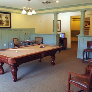 A cozy billiards room featuring a pool table, chairs, and elegant decor.