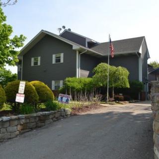 A large gray house with a driveway and landscaped garden on a sunny day.
