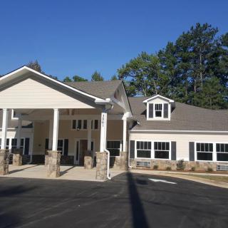 A suburban residential building with a covered entrance, surrounded by trees on a clear day.