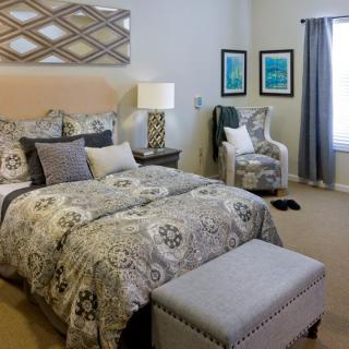 A cozy bedroom featuring a patterned bedspread, decorative pillows, and elegant lighting.
