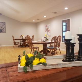 A cozy dining area with wooden tables and chairs, adorned with a decorative centerpiece featuring lemons and candles.
