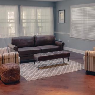 A cozy living room with a modern sofa, striped armchairs, and a patterned rug.