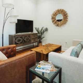 A cozy living room with modern furniture, featuring a TV stand, coffee table, and a decorative mirror.