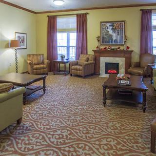 A cozy living room with a fireplace, sofas, and armchairs arranged around a coffee table.