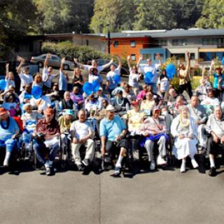 A joyful gathering of residents at a care facility, celebrating together outdoors.