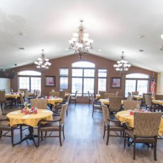 A spacious dining hall with multiple tables, chairs, and chandeliers.