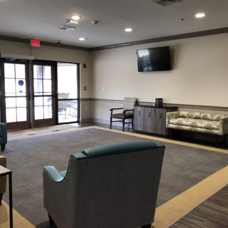 A modern waiting room with comfortable seating and a wall-mounted television.