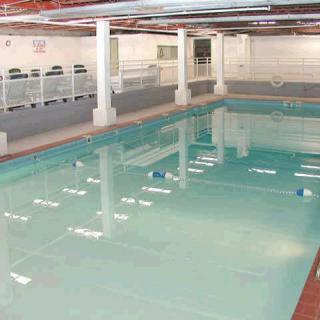 An empty indoor swimming pool with clear water and lanes marked.