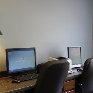An office workspace featuring two computers on a desk with chairs.