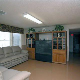 A living room with a beige couch and a large entertainment center featuring a television.