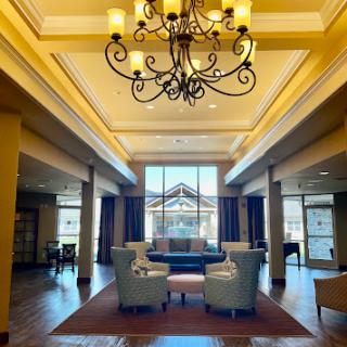 A beautifully designed lobby featuring elegant seating and a stunning chandelier, illuminated by ample natural light.