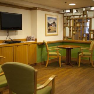 A cozy waiting room featuring comfortable chairs, a small table, and a television on the wall.