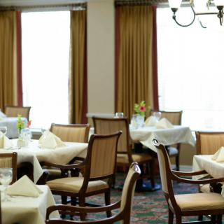 An elegant dining area with set tables and chairs, draped in soft lighting.