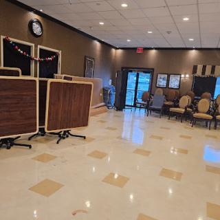 An elegantly designed lobby with wooden tables, comfortable seating, and a polished floor.