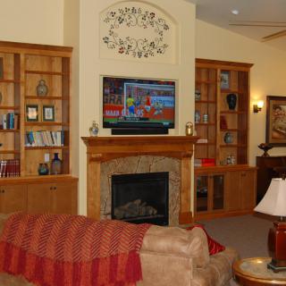A cozy living room featuring a fireplace, built-in bookshelves, and a television mounted above the mantel.